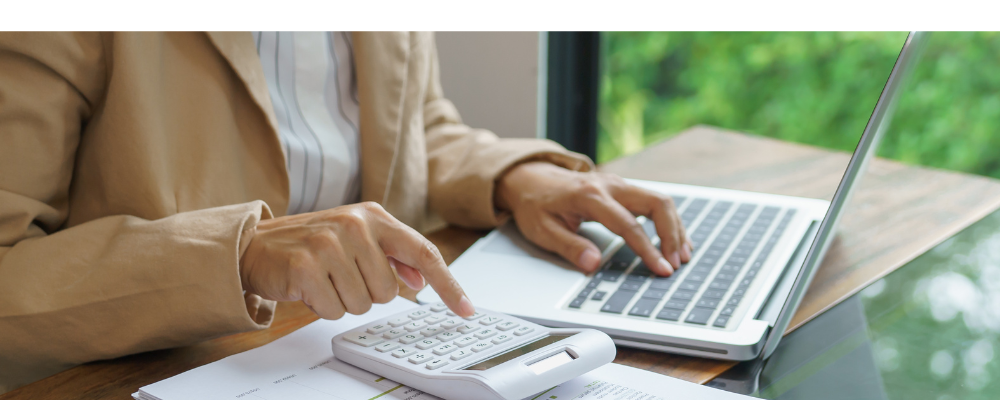 A woman using a calculator and computer