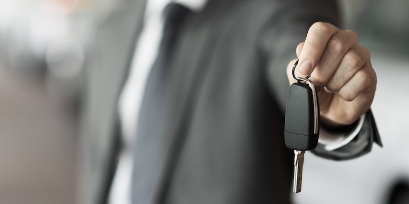 A salesman holds over the keys to a vehicle.